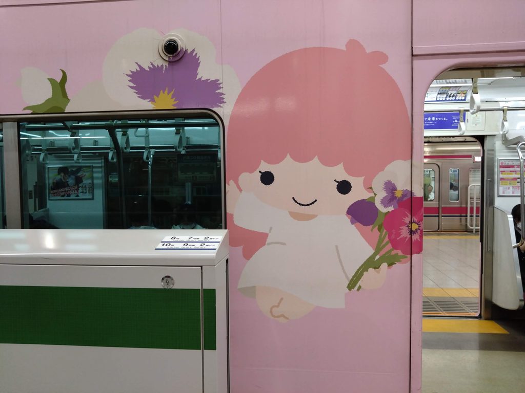 The Sanrio wrapped train arriving at Chofu station on the Keio Line, with Lala holding a bunch of flowers