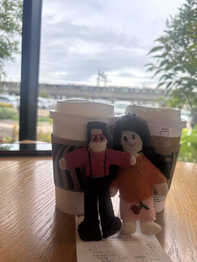 Tikoppi and Presley with two coffee cups at the Starbucks window, a train passing on the viaduct outside
