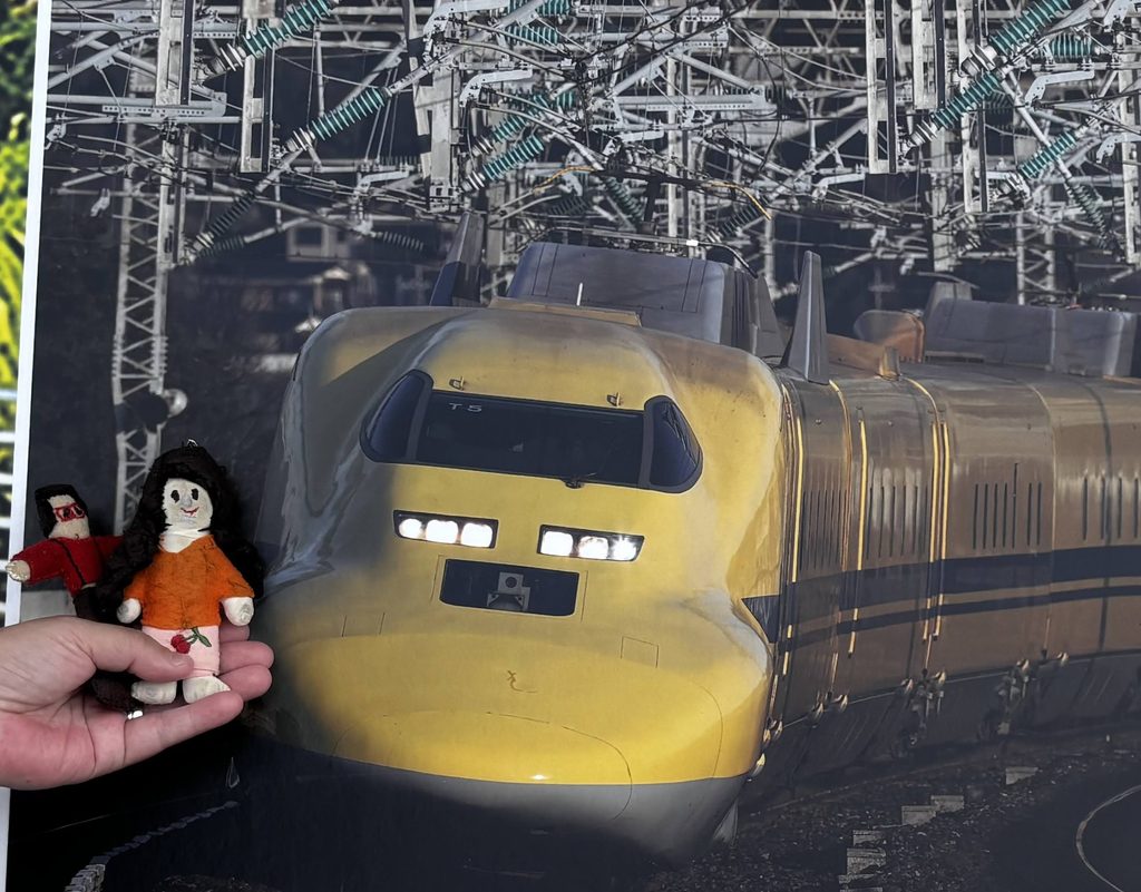 ドクターイエローの写真パネルの前で、手のひらに乗ったプレスリーとTikoppi
