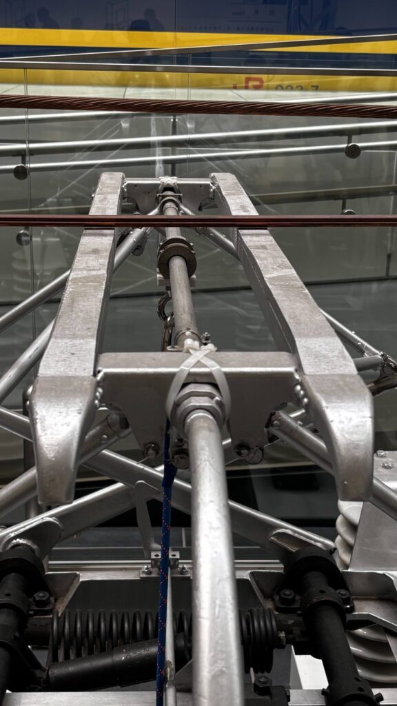 A full-size pantograph and contact wire, the contact strip visible where it meets the wire